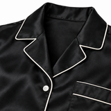 Close-up of ivory piping along the black silk nightshirt's collar and button placket.